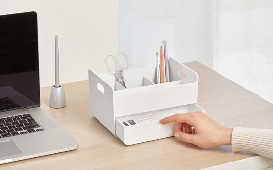 A hand opens the drawer of a white portable desk organizer perfect for small spaces.