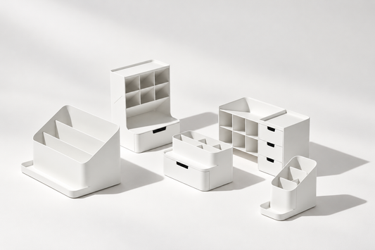 Five white desk organizers with file slots, divided compartments, trays, and drawers arranged on a light background.