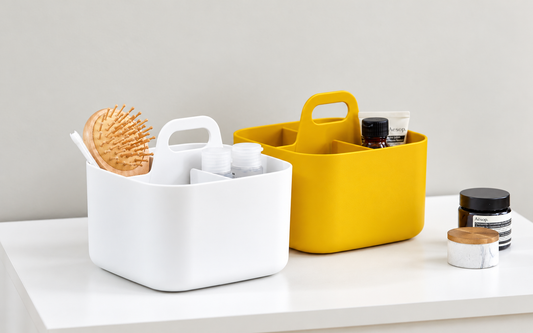 White and yellow Blue Ginkgo caddies organizing a hairbrush, toothbrush, and small toiletries on a white tabletop.