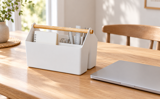 Blue Ginkgo medium storage basket holding work essentials beside a closed laptop on a dining table.