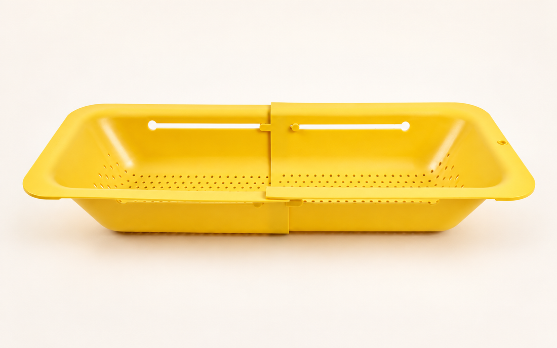 Yellow Blue Ginkgo expandable colander with drainage holes and an adjustable sliding design on a warm white background.