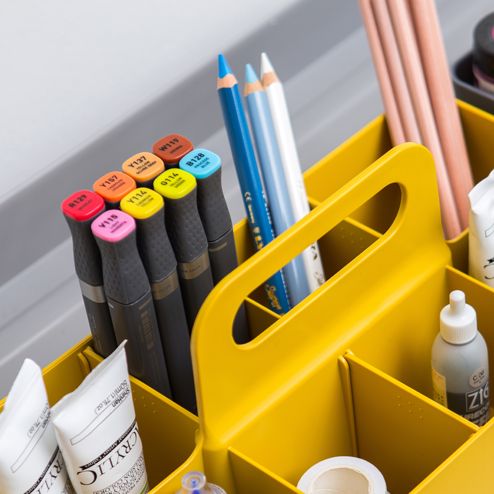 Yellow long rectangle caddy used to store pens, markers, pencils, and other stationery items.