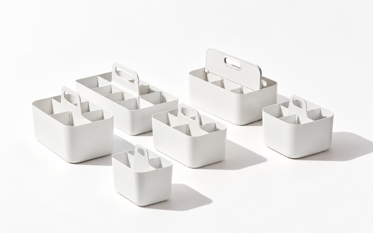 Six white storage caddies in different sizes, featuring carry handles and divided compartments, arranged on a light background.