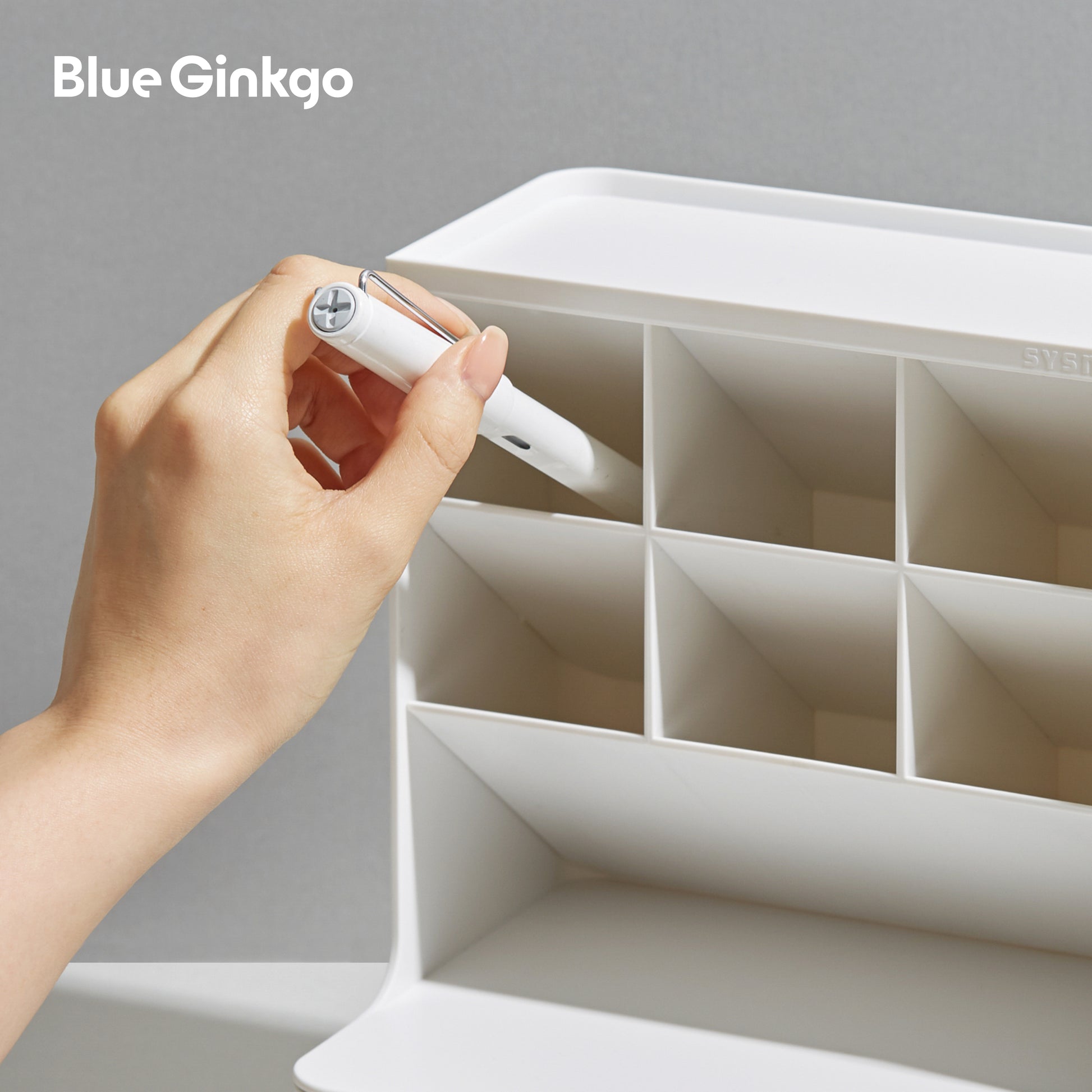 Hand placing a pen in a white Hive Desk Organizer.