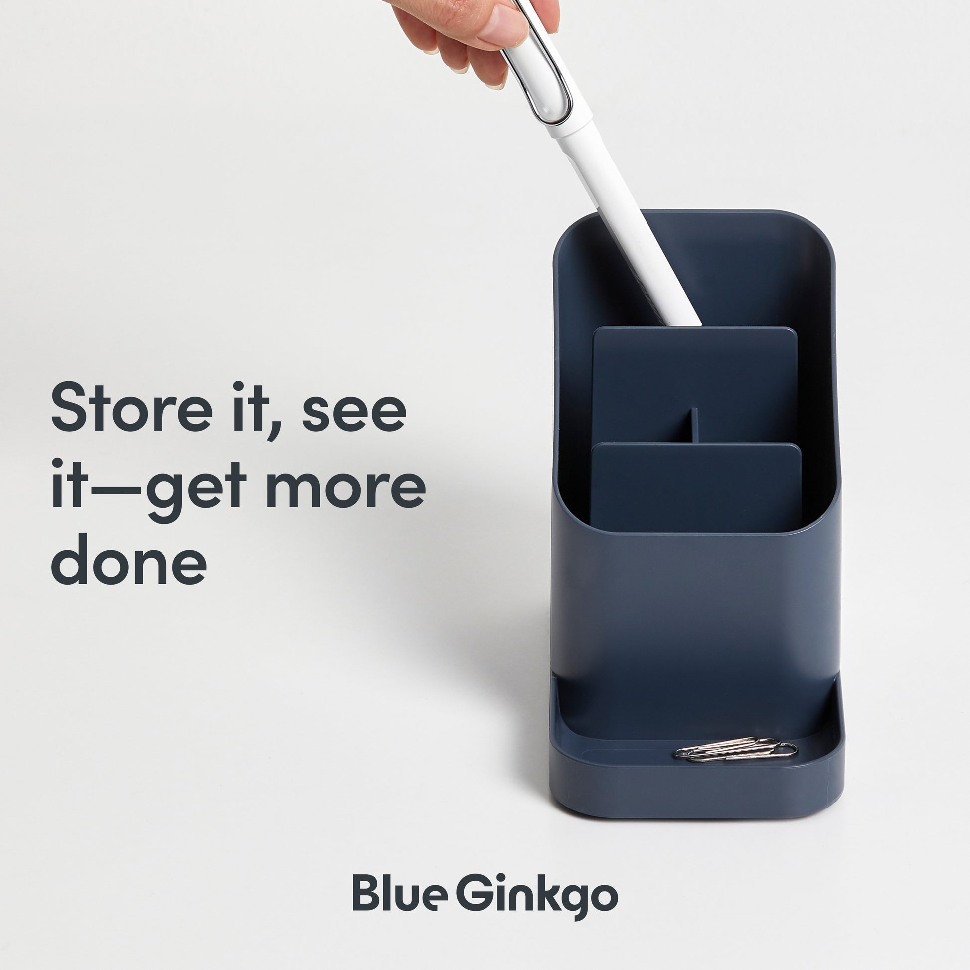 Blue desktop holder with stationery items on a light gray background.